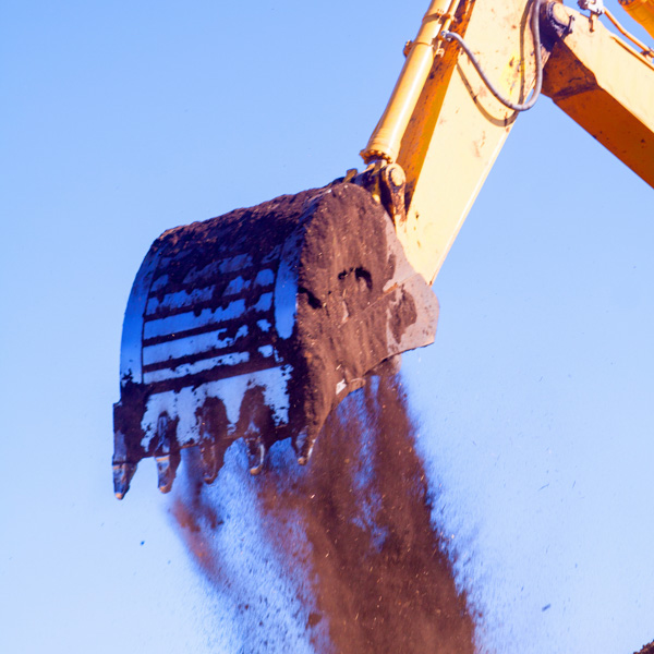 Excavator bucket dumping dirt mid-air