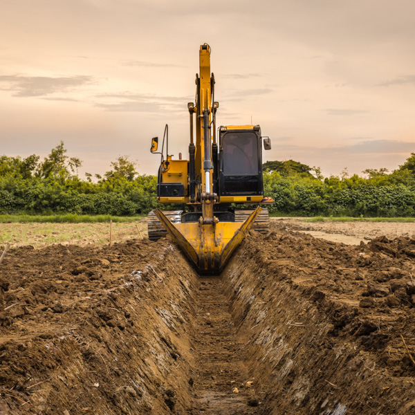 Excavator digging a trench at sunset