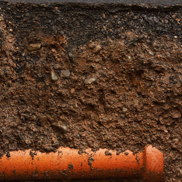 Underground view of orange conduit in soil