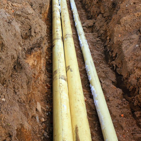 Exposed yellow underground gas pipes in trench