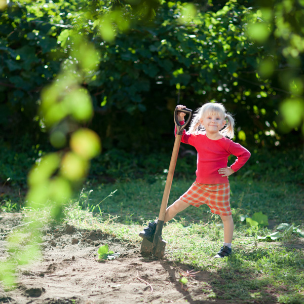 Girl using a shovel to dig in backyard